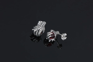 Detailed view of punk dragon claw earrings with red ruby beads on a black reflective surface