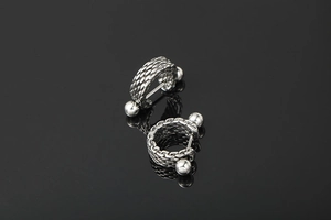 Detail of silver titanium steel earrings featuring chunky woven braided texture and punk style