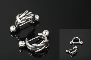 Detailed view of silver titanium steel knot earrings with ball ends on a black reflective surface