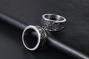 Detailed view of titanium steel cross rings with dot patterns on a black leather background