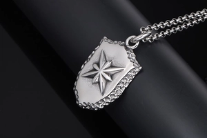 Détail macro du pendentif bouclier avec relief boussole et texture martelée vintage