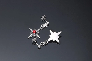 Dettaglio di orecchini a stella in argento con gemma rossa centrale e chiusura in metallo