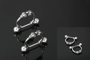 Makro-Detail von Edelstahl-Barbell-Piercings mit kronenförmigen Dekorringen