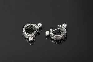 Detailed view of silver titanium steel earrings with woven punk texture and barbell closure