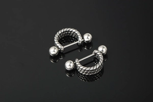 Detailed macro view of U-shaped stainless steel body jewelry with twisted rope texture