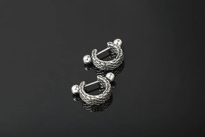 Detail of silver titanium steel earrings with woven mesh texture and polished spheres