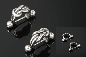 Detail shot of silver knot barbell earrings with dual metal spheres on black background