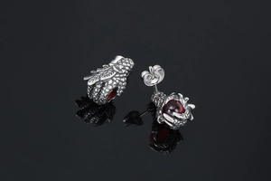 Detailed macro shot of punk style dragon claw earrings with red synthetic rubies