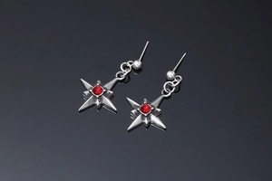 Dettaglio di orecchini a stella in argento con strass rosso su fondo nero