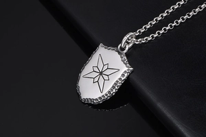 Gros plan du pendentif bouclier argenté avec étoile gravée et texture martelée