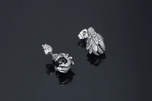 Close-up of punk style dragon claw studs with black beads on a reflective surface