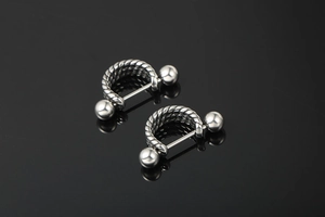 Macro detail of silver horseshoe ear studs with high-polish twisted cable texture
