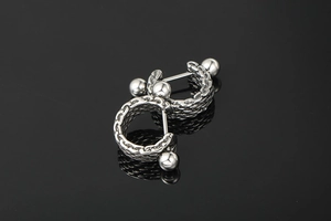 Detail of silver titanium steel earrings with woven chain texture on black background