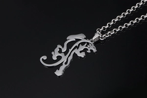 Macro detail of lion crest necklace pendant with metallic link chain on black surface