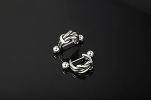 Macro shot of silver nautical knot earrings with high mirror polish on black surface