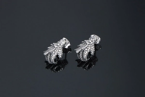 Detailed view of 3D punk dragon claw earrings with red stones on a black mirror surface