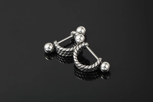 Macro detail of silver barbell studs with twisted rope texture and dual metallic beads