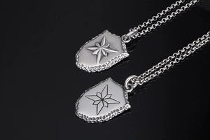 Détail de pendentifs boucliers argentés avec relief d'étoile sur fond noir brillant