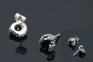 Détails macro des boucles d'oreilles serpent gothiques avec pierre noire et fini argent