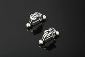 Close-up of polished silver knot design titanium steel earrings with mirror reflection