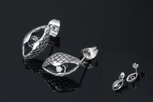 Detailed close-up of men's steel earring with scale texture and black center stone