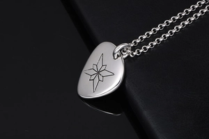Makroaufnahme von silbernem Plektrum-Anhänger mit Kompassstern und klassischer Kette