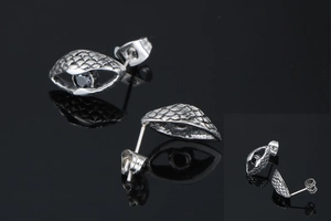 Detail view of retro silver stud earrings with snake scale texture and black gemstone