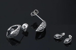 Detailed macro shot of vintage silver eye-shaped studs with black stones and scale texture