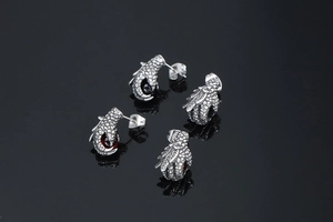 Close-up of punk style dragon claw stud earrings with vibrant red stones in silver finish