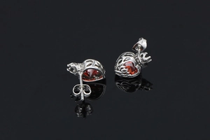 Detail of vintage crown heart stud earrings with ruby red stone on black mirror surface