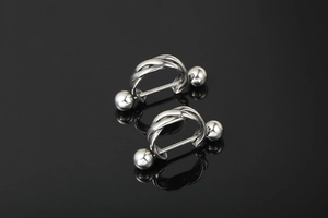 Dettaglio macro di piercing in acciaio al titanio argento con design a gabbia intrecciata