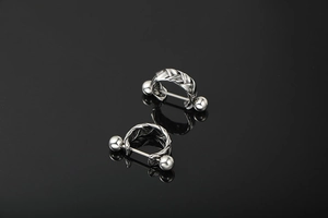Macro shot of silver woven braid twist earrings with smooth ball ends on black background