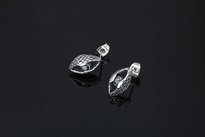 Close-up of men's evil eye stud earring with black stone and textured scale pattern