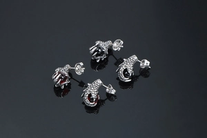Detail of 3D punk dragon claw earrings with red and black stones on black background