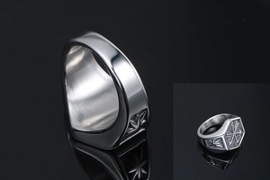 Macro detail of silver hexagonal signet ring with engraved crossed arrow pattern on top