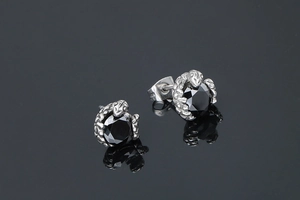 Vue macro des boucles d'oreilles serpent en argent avec gemmes noires sur fond miroir noir