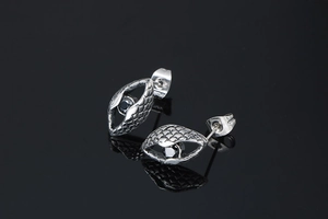 Macro shot of men's evil eye stud earring with black zircon and vintage steel scales