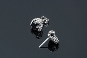 Détail de boucles d'oreilles serpent avec pierres noires et ciselure en métal argenté