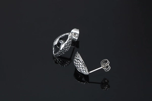 Detailed view of silver snake scale textured earrings with black stone inlay on reflective black surface