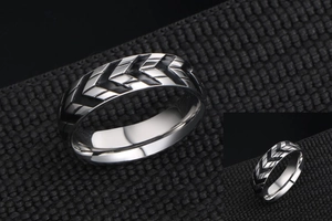 Macro detail of men's titanium steel ring with black tire tread patterns and silver finish