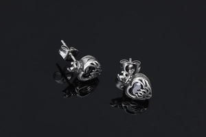 Macro shot of silver crown earrings with black heart-shaped gemstone and punk engraving