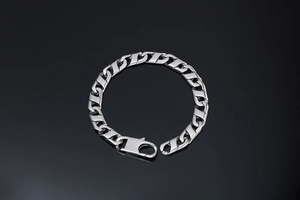 Détail du bracelet gourmette en acier titane avec fermoir mousqueton sur fond noir