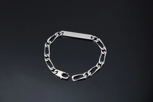 Vue macro du bracelet chaîne Figaro en argent avec plaque d'identité polie et fermoir homard