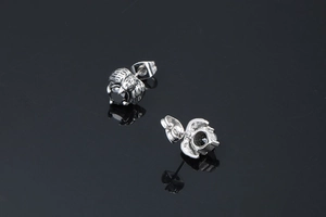 Macro view of raven claw stud earring holding black agate stone with silver feather detail