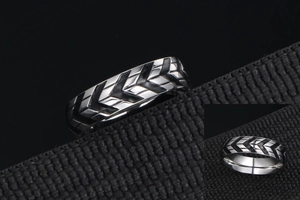 Macro shot of silver tire tread pattern ring on black textured strap with detail view