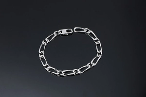 Vue macro du bracelet chaîne Figaro argenté avec fermoir mousqueton et fini poli