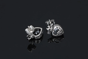 Detailed close-up of heart-shaped black gemstone earrings with gothic silver filigree
