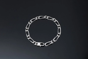 Gros plan du bracelet gourmette Figaro en argent poli avec un fermoir mousqueton sûr