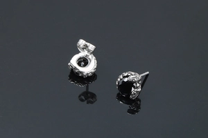 Vue macro des boucles d'oreilles serpent en argent avec pierre noire et détails gothiques