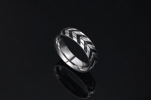 Macro shot of silver titanium steel ring with black V-shaped tire tread pattern details